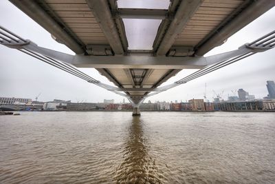 Bridge over river against sky in city