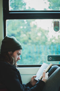 Man reading book while sitting in bus