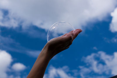 Low angle view of person hand against sky