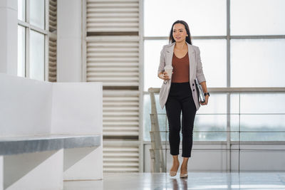 Portrait of woman standing against staircase