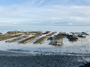 Scenic view of oyster farm at sea against sky during winter