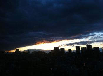 Cityscape against cloudy sky at sunset