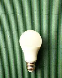 Close-up of light bulb on green textured table