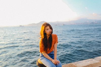 Young woman standing in sea against sky