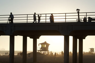 Silhouette people on pier against clear sky