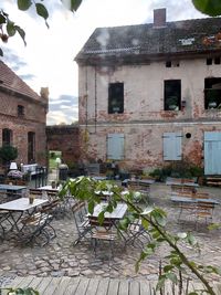Empty chairs and tables against buildings in city