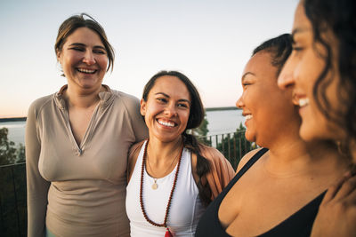 Multiracial happy female friends laughing together during sunset