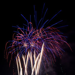 Low angle view of fireworks against sky at night