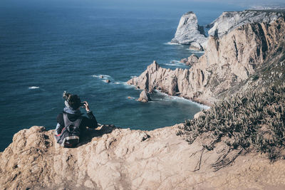 High angle view of people sitting on rock by sea