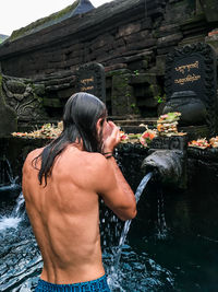 Shirtless man standing in water at temple