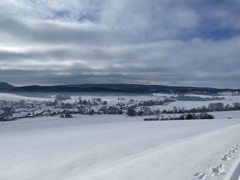 Scenic view of snow covered land against sky