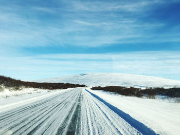 Snow covered road against sky