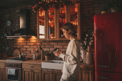 Portrait of candid authentic boy teenager holiday cooking in kitchen at wooden lodge xmas decorated