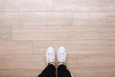 Low section of man standing on hardwood floor