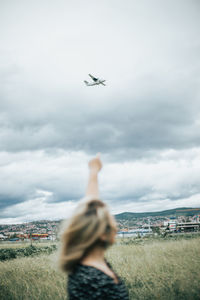 Rear view of airplane flying over cityscape against sky