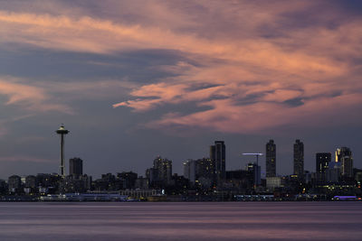 Illuminated buildings against cloudy sky during sunset