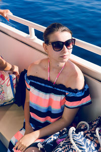 High angle view of young woman wearing sunglasses sitting in boat