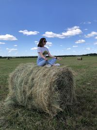 Side view of woman sitting on field
