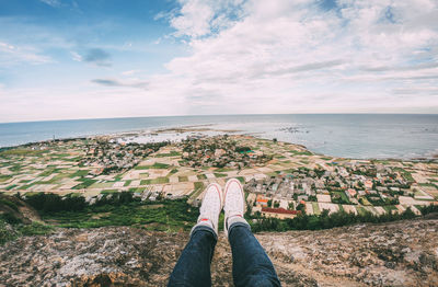 Low section of person by sea against sky