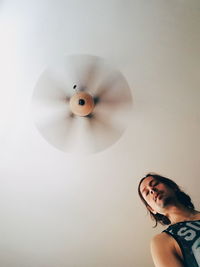 Low angle view of man against spinning ceiling fan at home