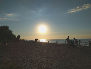 Silhouette people on beach against sky during sunset