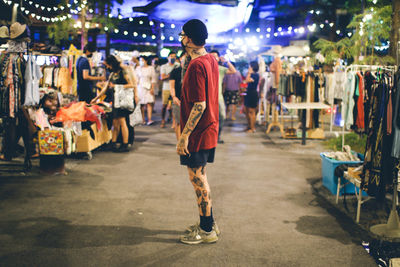 Rear view of man walking on illuminated street at night