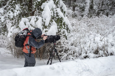 Man photographing on snow covered field