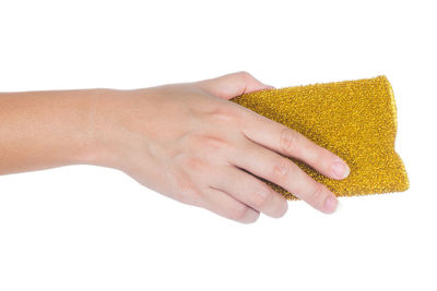 Cropped hand holding cleaning sponge against white background