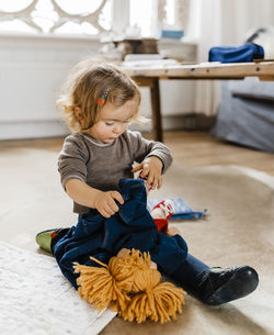 Cute girl playing with toys on floor at home