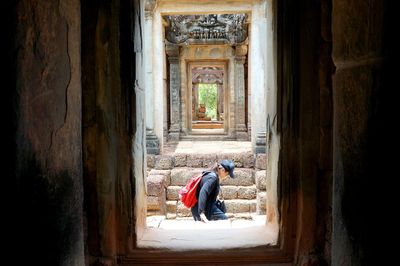 Rear view of man walking in temple outside building