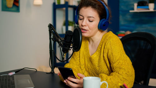 Young woman using mobile phone while sitting on table