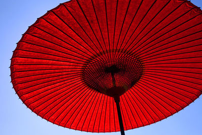 Low angle view of red paper umbrella against sky