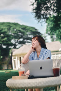 Woman using phone while sitting on table