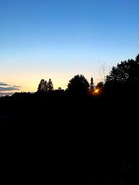 Silhouette trees on field against clear sky during sunset