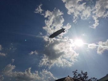 Low angle view of sun shining through clouds