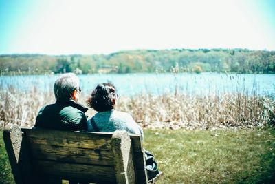 Rear view of people looking at lake against sky