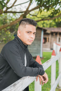 College man standing by the white wooden fence young entrepreneur in black suit looking