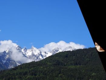 Low angle view of snowcapped mountains against blue sky