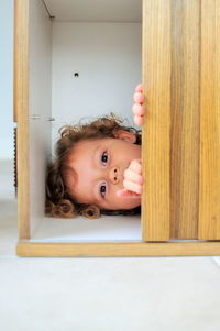 Close-up of girl lying in cabinet at home
