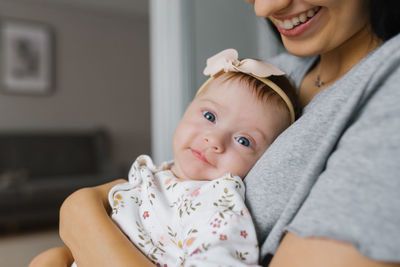 Young woman mom with baby girl on hands at home