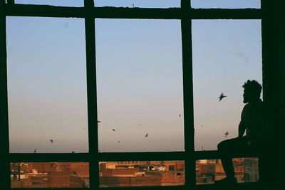 Silhouette man standing by glass window