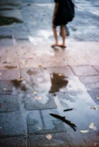 Low section of woman standing on puddle