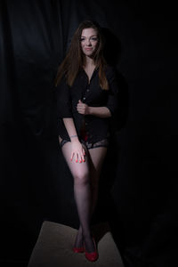 Portrait of female model standing against black backdrop