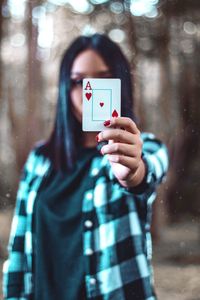 Portrait of woman covering face with card