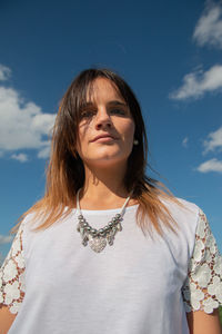 Portrait of young woman standing against sky