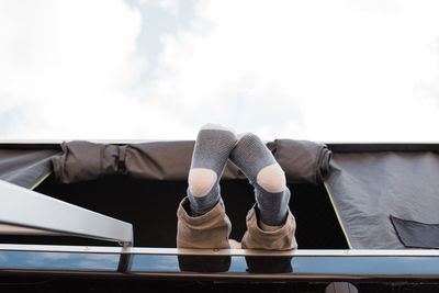 Child's feet hanging out of a roof top tent whilst camping