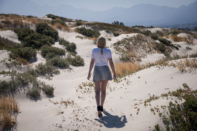 Rear view of woman walking on sand dune