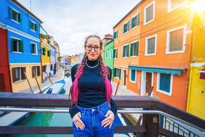 Portrait of young woman standing against building