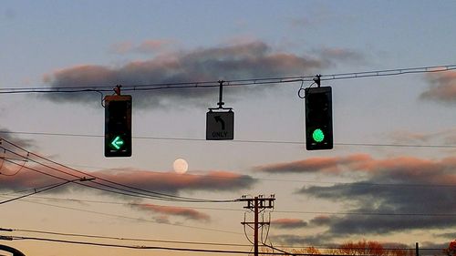 Low angle view of electricity pylon against sky during sunset