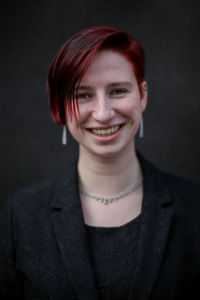 Portrait of young woman against black background